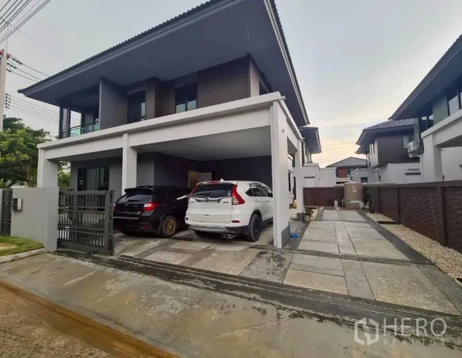 Detached House for rent or sale in Lam Luk Ka, Pathum Thani - Modern two-storey detached house at Setthasiri Wongwaen–Lamlukka with a covered two-car carport and gated driveway.