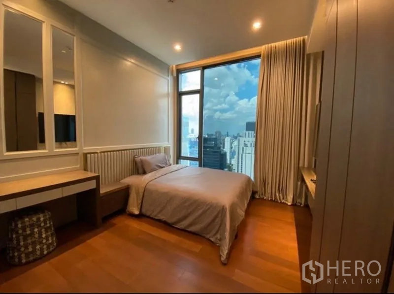 Condominium for rent in Khlong Toei, Bangkok - Secondary bedroom with large window, dressing table and a wide city view.