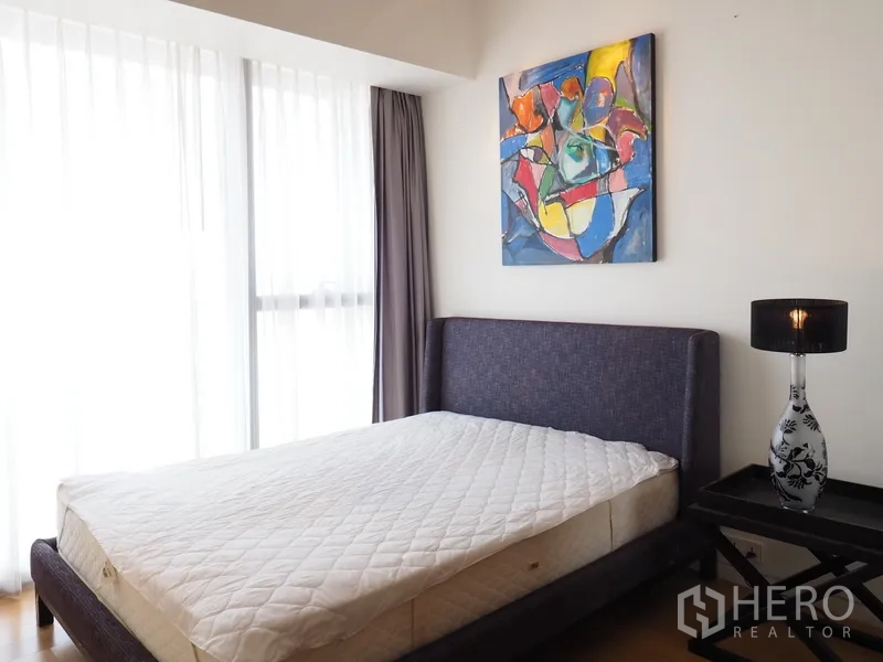 Condominium for rent in Sathon, Bangkok - Guest bedroom with upholstered bed, abstract artwork and soft natural light.