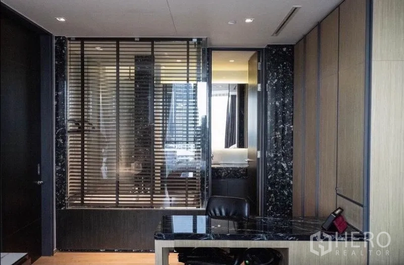 Condominium for rent in Khlong Toei, Bangkok - Work desk with black marble top facing a window into the bathroom with blinds.