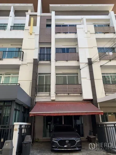 带办公室的家 出租在Wang Thonglang, Bangkok - 四层现代联排家用办公楼外立面，带红色雨棚与私家车位，位于曼谷。