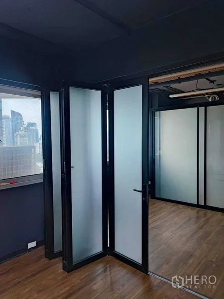 办公空间 出租在Watthana, Bangkok - 折叠磨砂玻璃门，通向采光充足的房间与天际线景观。