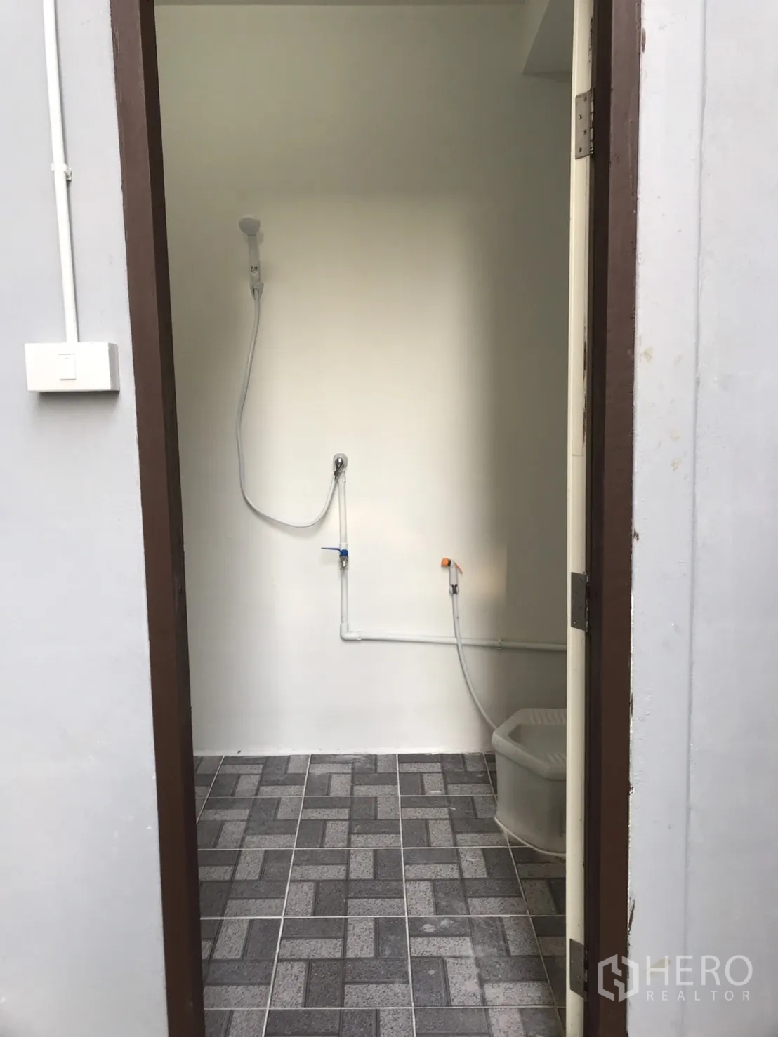 Warehouse for rent in Lam Luk Ka, Pathum Thani - Bathroom entrance with handheld shower and patterned floor tiles.