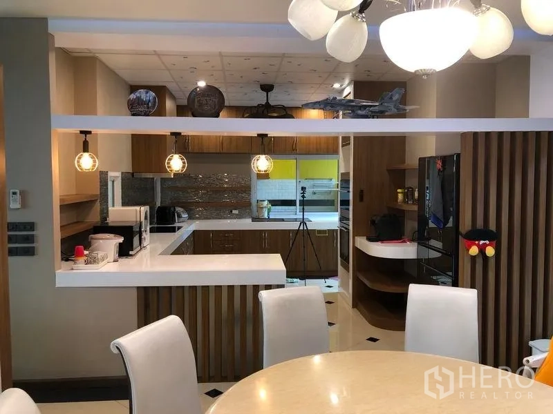 Detached House for sale in Wang Thonglang, Bangkok - Open-plan kitchen with white island, wood cabinetry, backsplash tiles and pendant lighting.