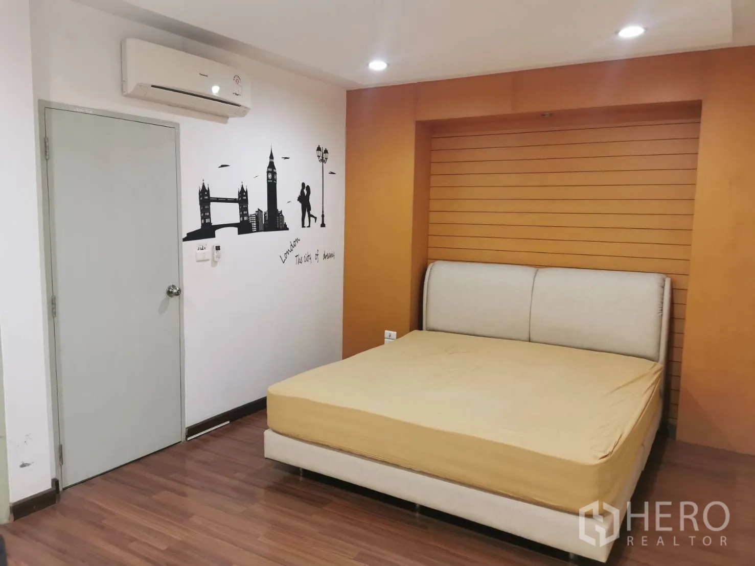 Townhouse for rent or sale in Yan Nawa, Bangkok - Master bedroom with recessed headboard feature wall, air conditioning and warm wood accents.