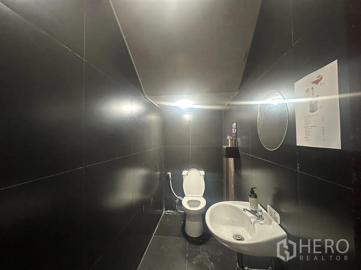 带办公室的家 出租在Pathum Wan, Bangkok - 黑色瓷砖卫生间，配坐便与壁挂式洗手盆，适合员工与顾客。