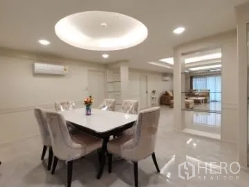 Apartment for rent in Watthana, Bangkok - Dining zone under a circular ceiling feature with a six-seat table, looking toward the living room.