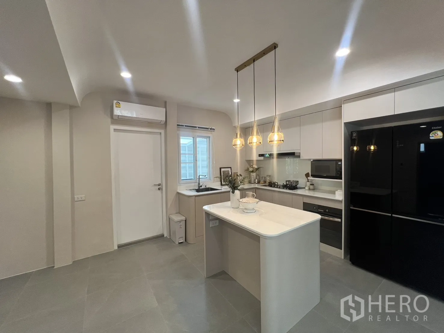 Detached House for rent in Mueang Samut Prakan, Samut Prakan - Kitchen opening to living area with island and pendant lights.
