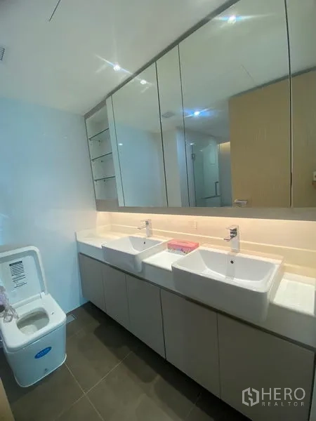 Apartment for rent in Watthana, Bangkok - Main bathroom with double vanity, large mirrored cabinets and contemporary lighting.
