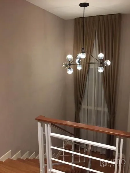 Detached House for rent or sale in Khlong Toei, Bangkok - Staircase corner with modern sputnik chandelier and tall curtained window.