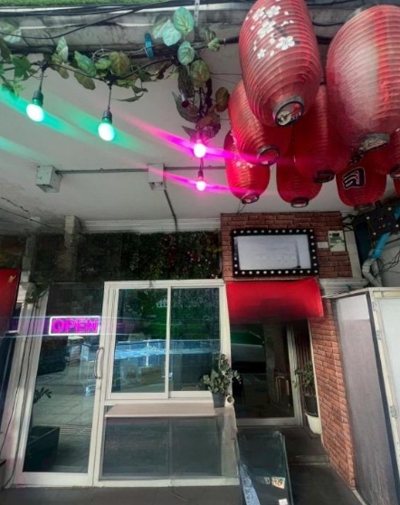 Retail Space for rent in Watthana, Bangkok - Glass-fronted retail entrance with sliding door, neon Open sign, red lanterns, and brick wall on Sukhumvit near BTS Thonglor.
