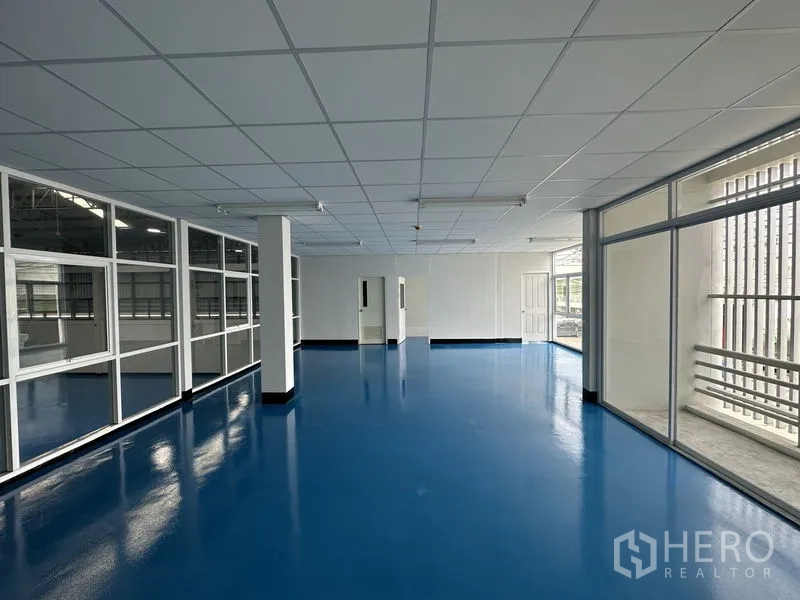Factory for rent in Khlong Luang, Pathum Thani - Upstairs office level with glass partitions, drop ceiling and blue epoxy flooring.