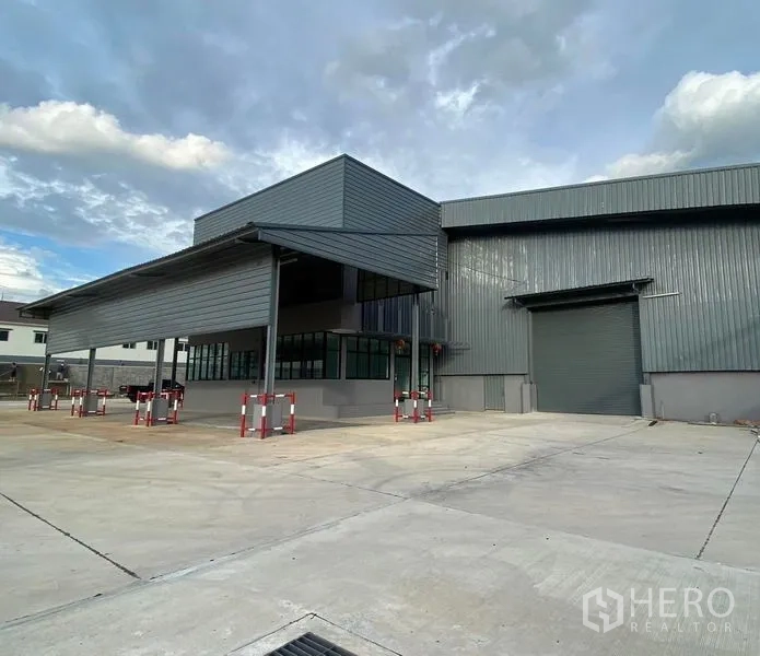 Warehouse for rent in Bang Phli, Samut Prakan - Front facade of steel‑clad warehouse with large canopy, roller door and spacious paved yard for container access.