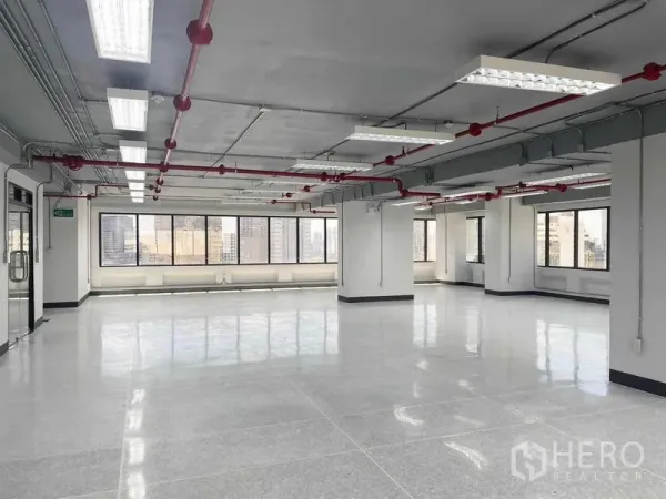 办公空间 出租在Bang Rak, Bangkok - 开放式办公楼层，顶面照明与消防喷淋，宽窗可见城市景色。
