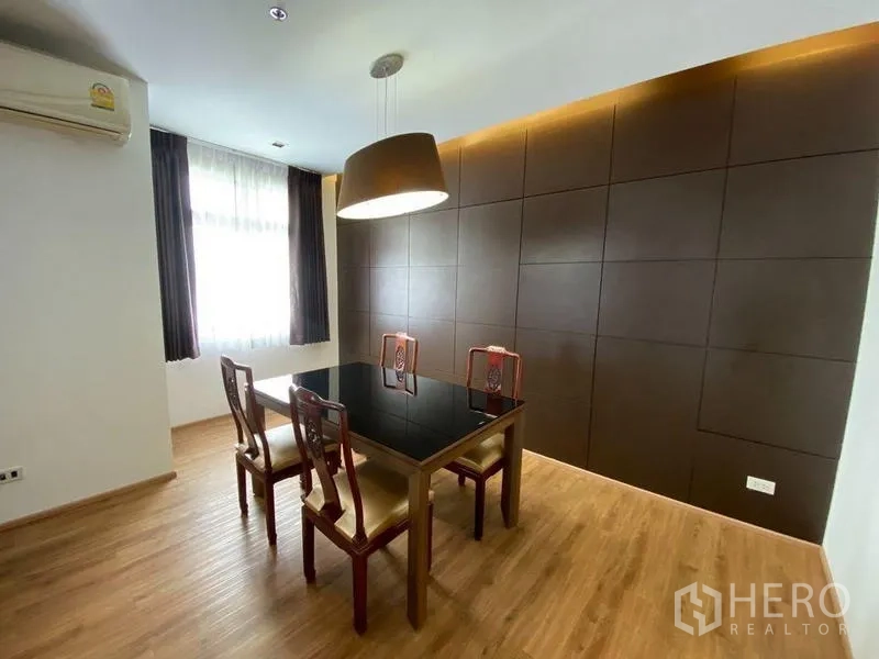 Condominium for rent in Khlong Toei, Bangkok - Dining area with four-seat glass table, pendant light and dark accent wall.