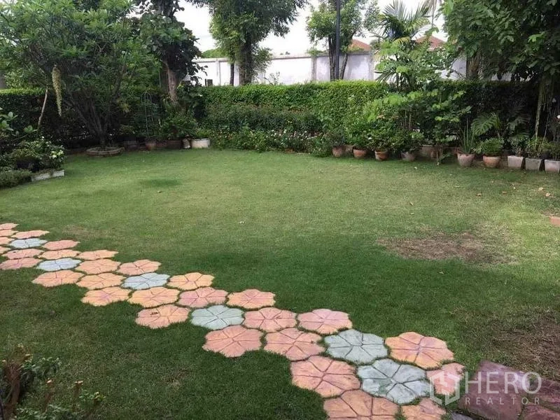 Detached House for sale in Bang Kruai, Nonthaburi - Spacious green lawn bordered by shrubs with a colorful stone walkway.