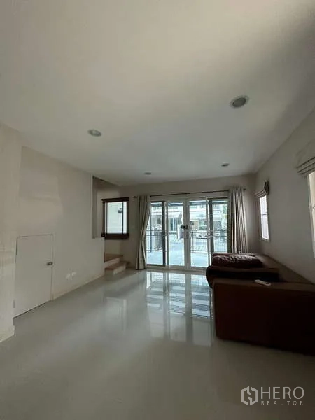 联排别墅 出租或出售在Wang Thonglang, Bangkok - 宽敞客厅，正面推拉门采光好，并有通往楼上的楼梯。