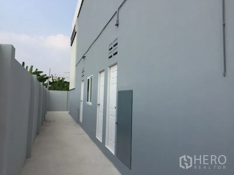 货栈 出售在Khlong Luang, Pathum Thani - 仓库侧边服务通道，灰色外墙配服务门与窗。