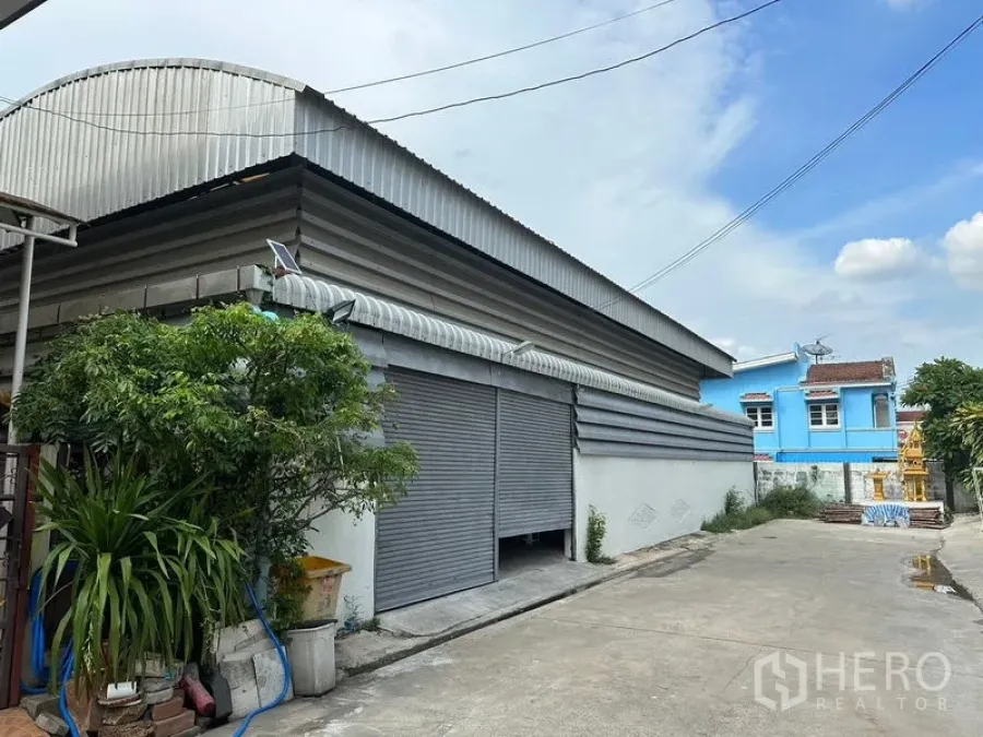 Warehouse for rent in Bueng Kum, Bangkok - Warehouse exterior with wide rolling shutter doors and corrugated metal roof.