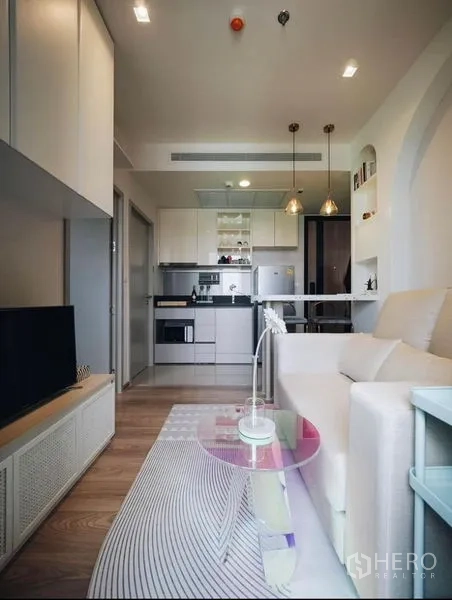 Condominium for rent - Open-plan living area with pendant lights, sofa and kitchenette.