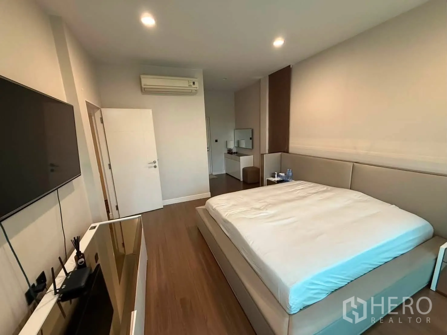 Detached House for rent in Bang Kapi, Bangkok - Bedroom with wall-mounted TV opposite a large bed and side cabinet.