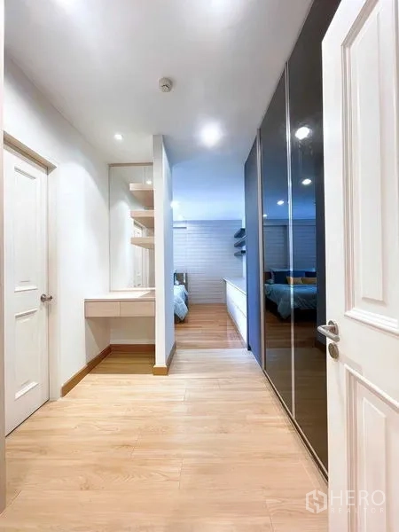 Condominium for rent - Corridor with built-in wardrobe and small dressing table leading to a bedroom with wooden floors.