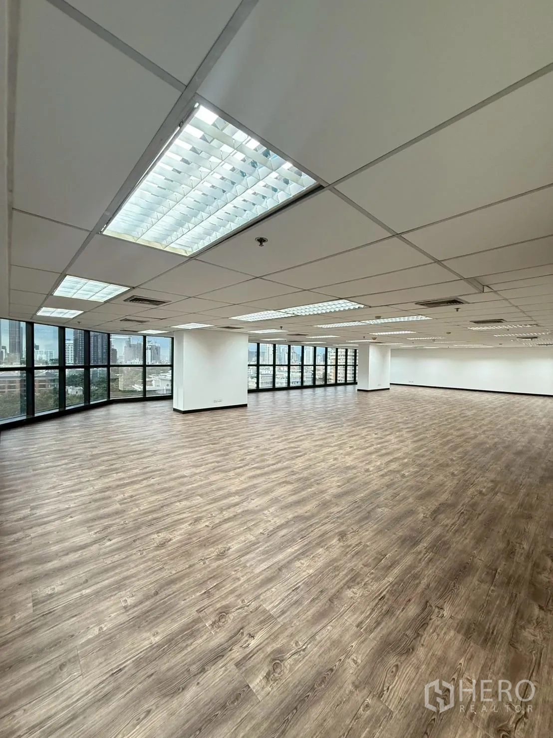 Office Space for rent in Watthana, Bangkok - Open workspace with suspended ceiling, air-conditioning vents, and expansive windows.