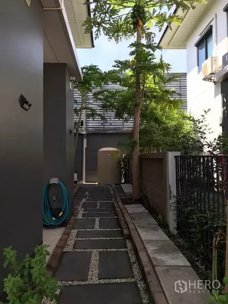 Detached House for rent in Bang Kapi, Bangkok - Stone-paved side walkway with trees and a side entrance at the detached house.