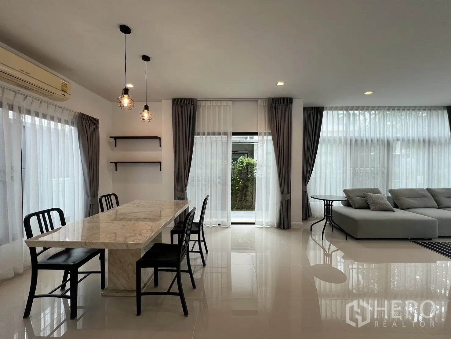 Detached House for rent in Bang Kapi, Bangkok - Airy room showing dining table and sofa with curtain-draped windows.