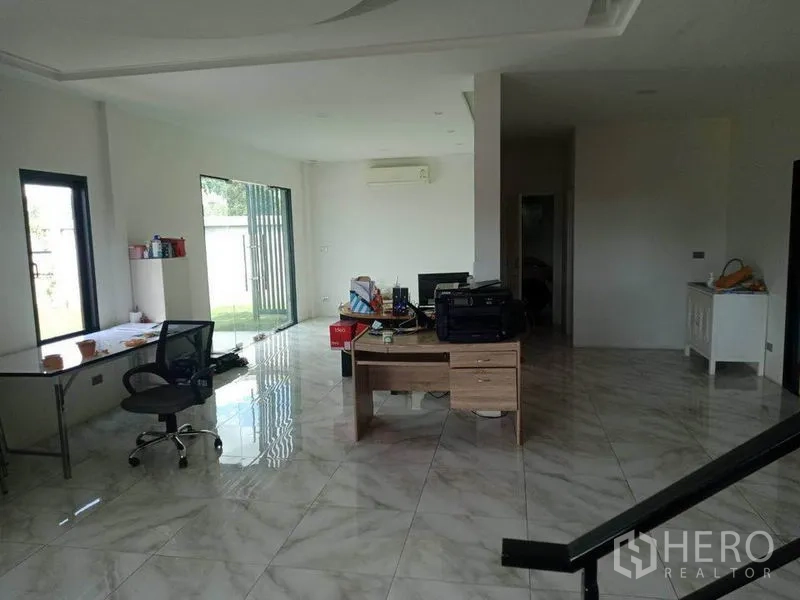 Warehouse for sale in Lam Luk Ka, Pathum Thani - Ground-floor office area with glossy tile floors, desks and a sliding glass door to the garden.