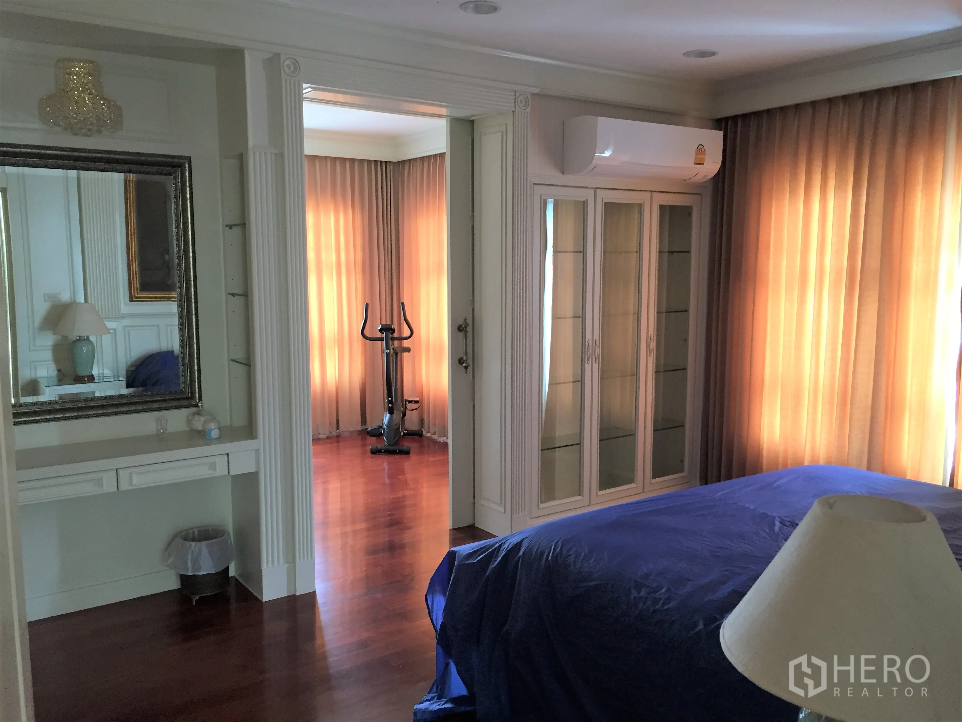 Detached House for rent in Saphan Sung, Bangkok - Spacious bedroom with full-height curtains, glass display cabinet and a small workout corner.