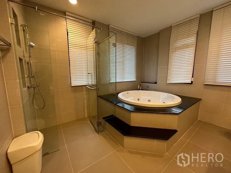 Detached House for rent or sale in Khan Na Yao, Bangkok - Bathroom featuring a raised jacuzzi bathtub, glass shower and corner windows.