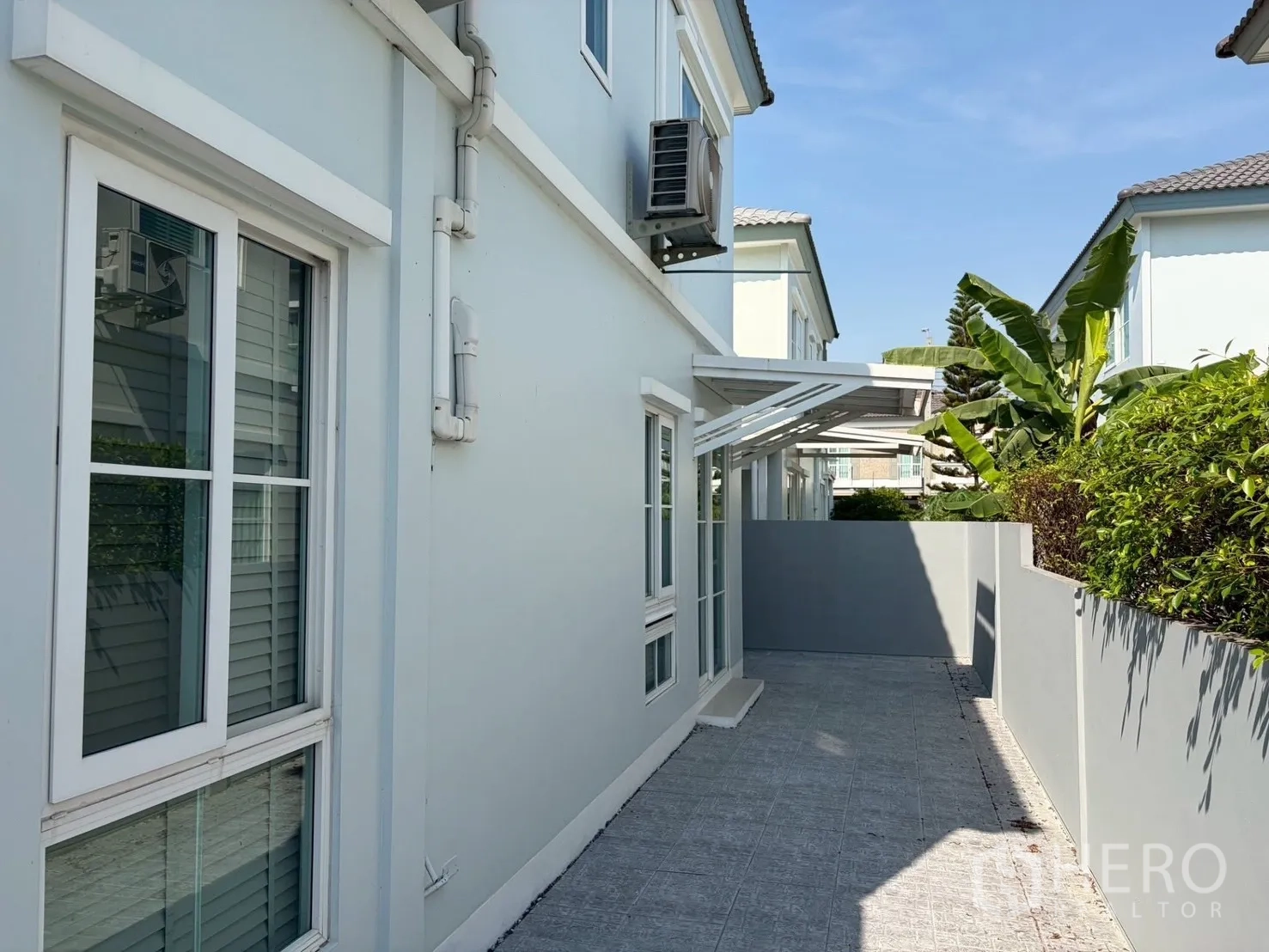 半独立式住宅 for rent in Prawet, Bangkok - 房屋侧边铺砖庭院，私密围墙与绿篱及推拉窗。