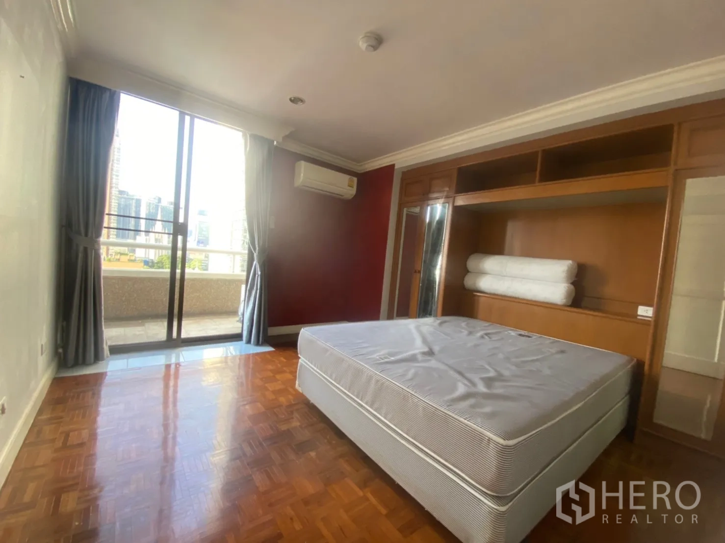 Condominium for rent or sale in Watthana, Bangkok - Bright bedroom with parquet floor, built-in wardrobe and balcony access overlooking the Asoke skyline.