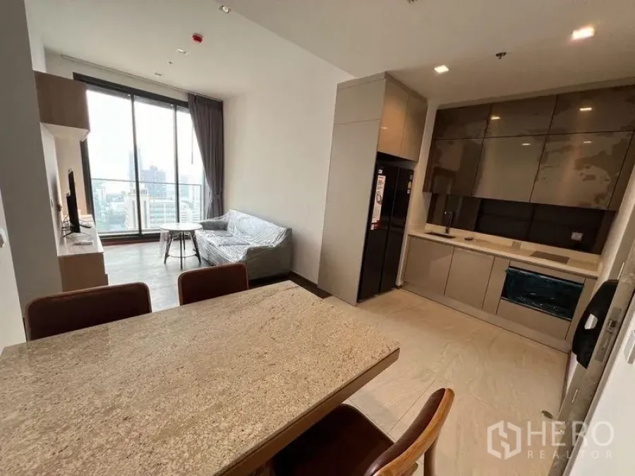 Condominium for rent in Ratchathewi, Bangkok - Open-plan dining and kitchen area adjoining living space with city-facing balcony.