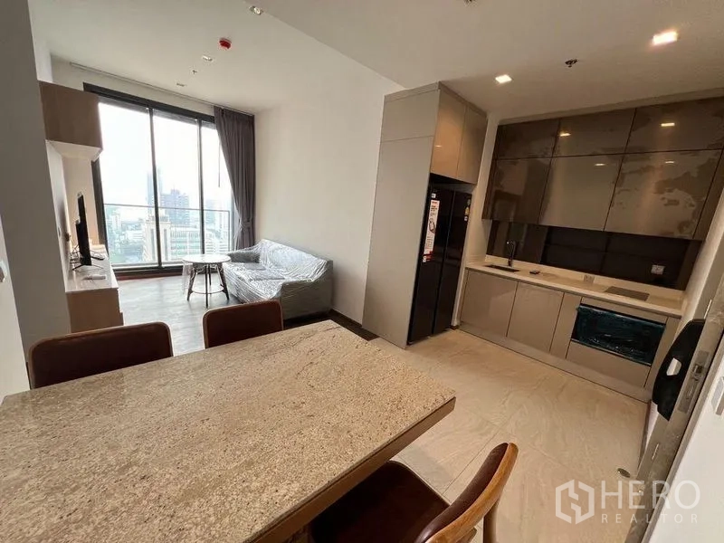 Condominium for rent in Ratchathewi, Bangkok - Open-plan dining and kitchen area adjoining living space with city-facing balcony.