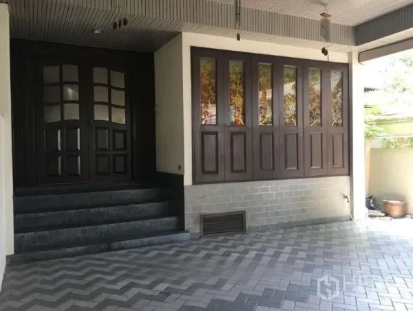 Townhouse for rent in Khlong Toei, Bangkok - Covered entrance and carport with steps leading to dark wood double doors.