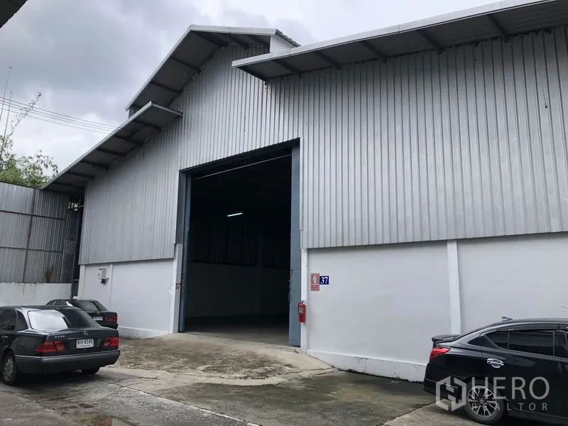 货栈 出租在Pak Kret, Nonthaburi - 金属外墙仓库立面，宽大装卸入口与停车区，位于帕克烈。