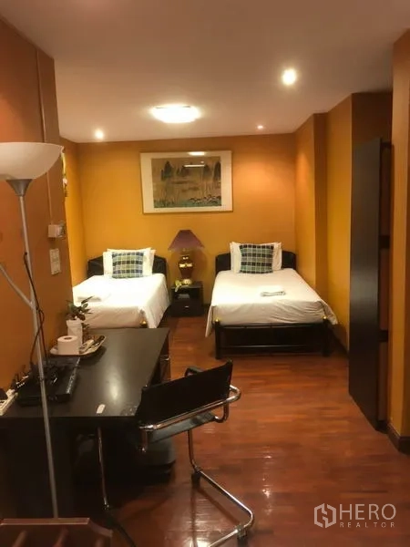 อาคารพาณิชย์ ให้เช่าในBang Rak, Bangkok - ห้องพักเตียงเดี่ยวสองเตียง พร้อมโต๊ะทำงานและพื้นไม้ ภายใต้ไฟดาวน์ไลท์