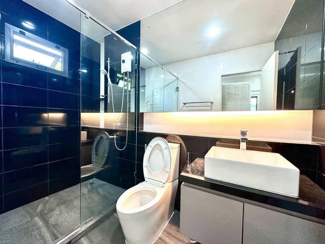 Detached House for rent in Bang Kapi, Bangkok - Contemporary bathroom with glass shower, toilet, wide mirror and vanity.