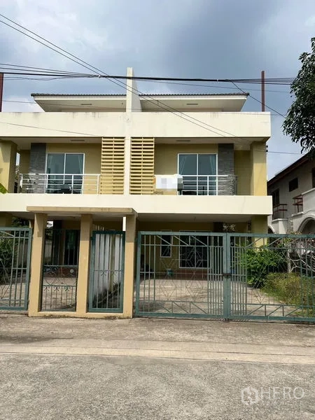 Townhouse for rent in Bang Kapi, Bangkok - Modern two-storey townhouse exterior in Bangkok with gated driveway and balcony fronts.