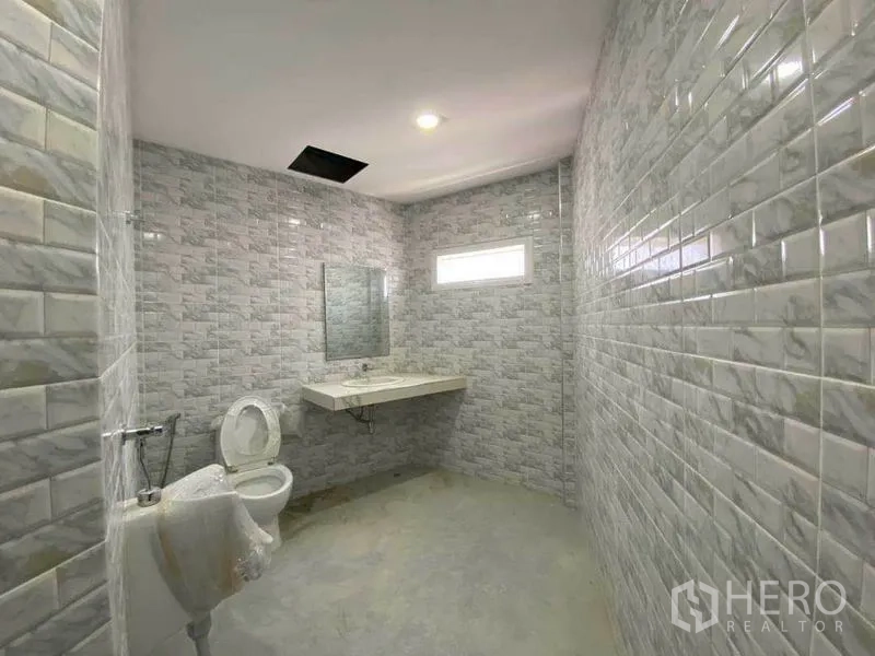 Retail Space for rent in Khlong Toei, Bangkok - Spacious restroom with grey wall tiles, toilet and vanity.