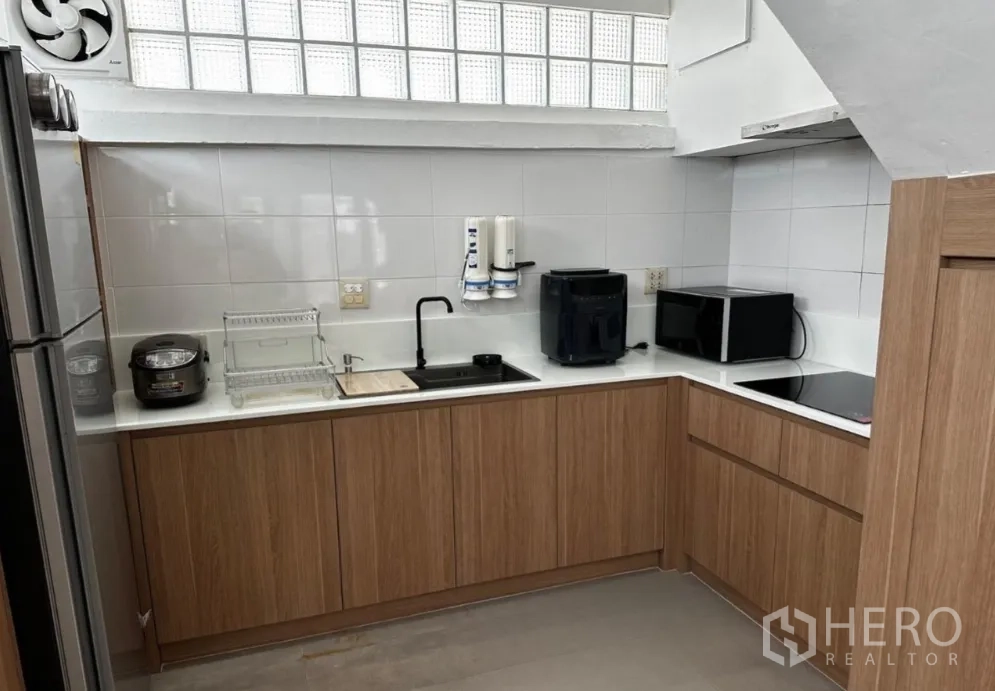 联排别墅 for rent in Sathon, Bangkok - 现代L形厨房，木质橱柜、瓷砖墙面与家电设备。