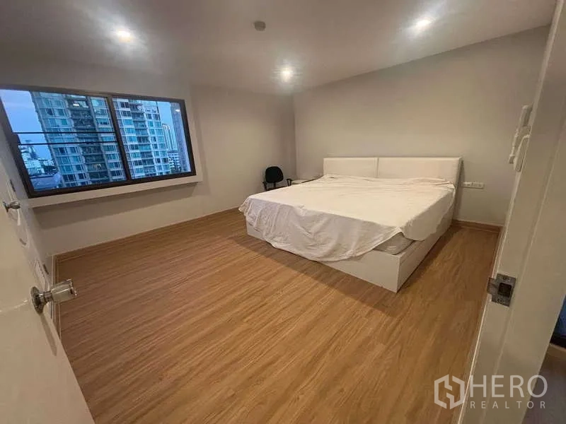 公寓 出售 - 温馨卧室，特大床、木地板与城市景观窗。