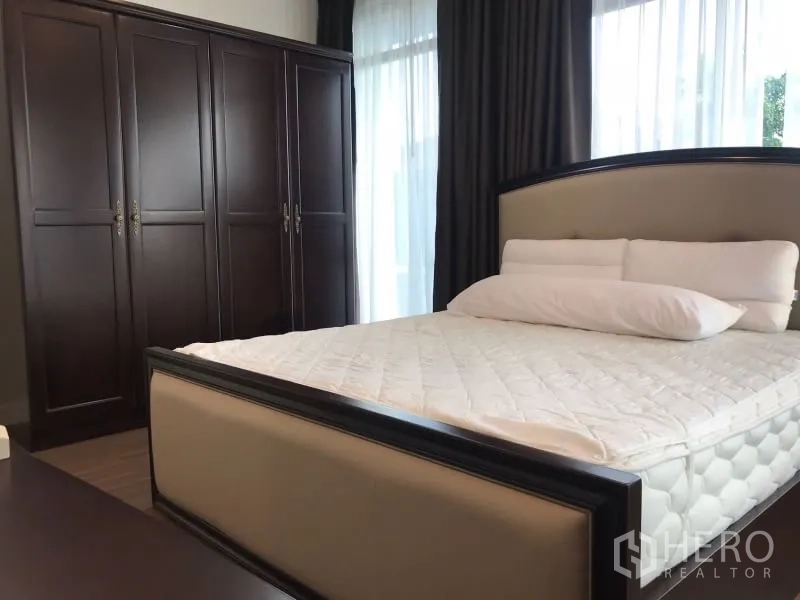 บ้าน ให้เช่าในBang Kapi, Bangkok - ห้องนอนอบอุ่น เตียงคู่ ตู้เสื้อผ้าไม้สีเข้ม และม่านโปร่ง