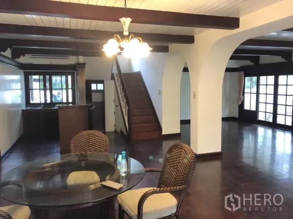 Detached House for rent in Khan Na Yao, Bangkok - Open-plan dining area with chandelier, arched doorways, staircase and garden-facing doors.