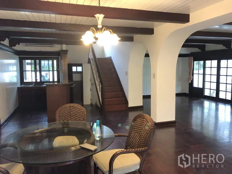 Detached House for rent in Khan Na Yao, Bangkok - Open-plan dining area with chandelier, arched doorways, staircase and garden-facing doors.