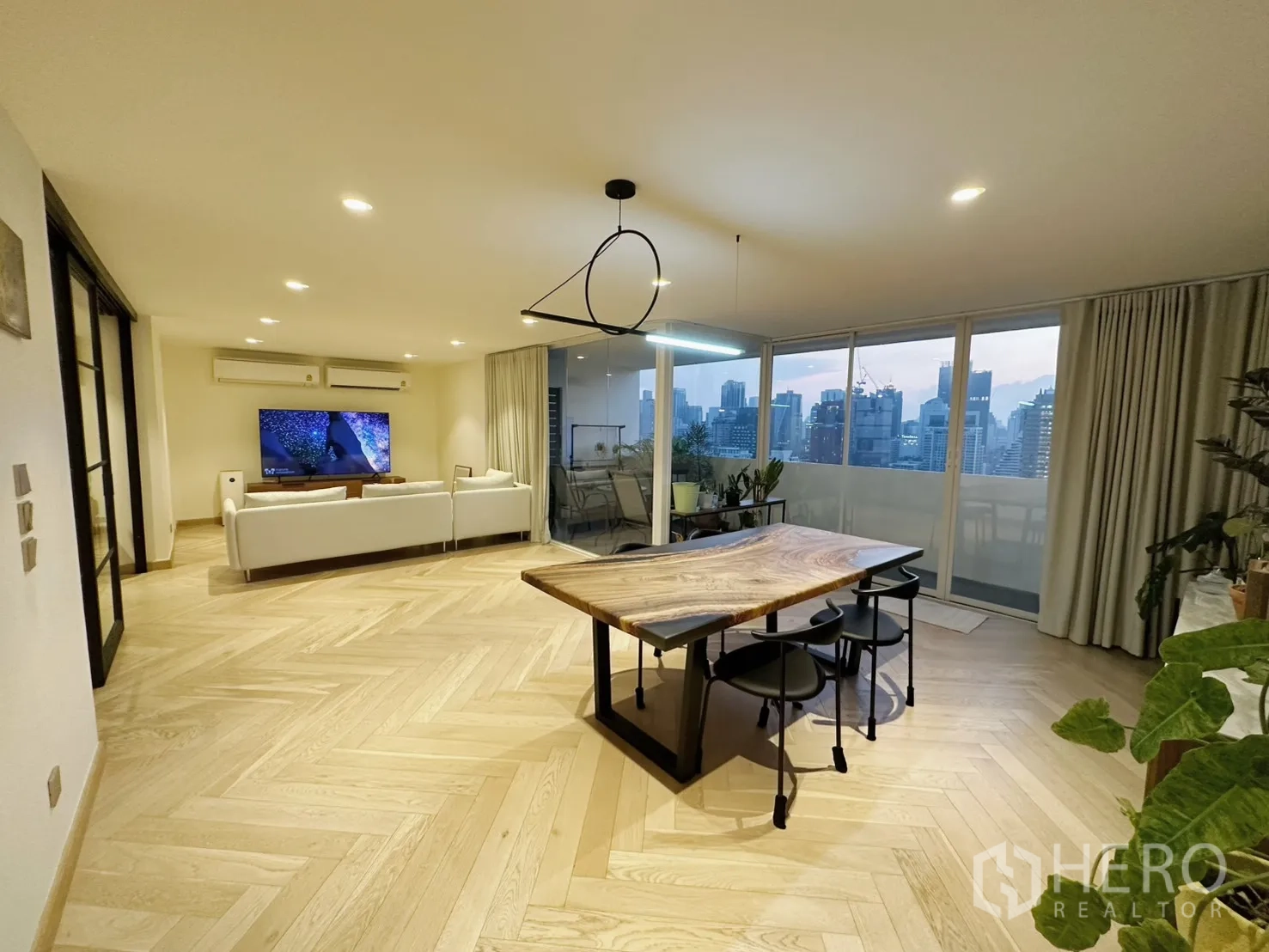 Condominium for rent or sale in Watthana, Bangkok - Spacious open living and dining area with a city panorama through sliding glass.