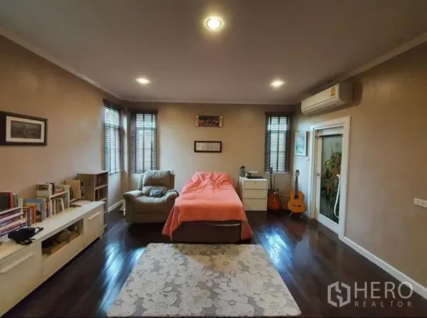 Detached House for sale in Sai Mai, Bangkok - Cozy bedroom with wood flooring, armchair, bookshelves and air conditioner.