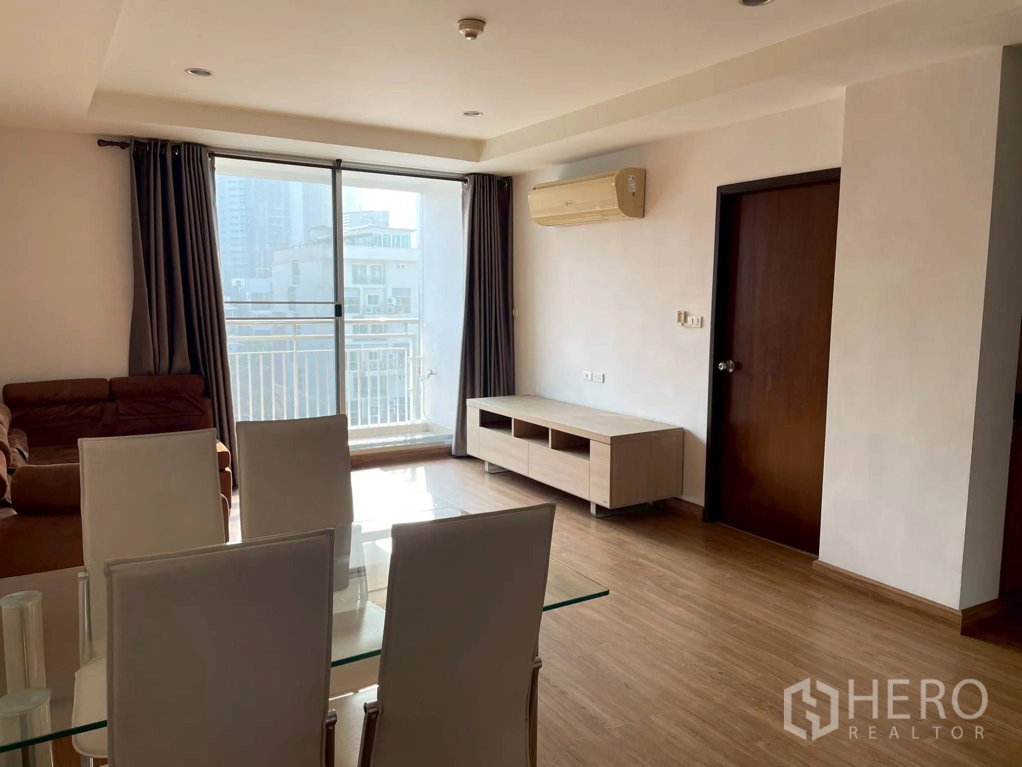 อพาร์ทเมนท์ for rent in Khlong Toei, Bangkok - ห้องนั่งเล่นและทานอาหารสว่างพร้อมประตูบานเลื่อนออกสู่ระเบียงวิวเมือง